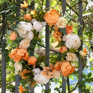 Künstlicher Pfingstrosenkranz mit orangen und cremefarbenen Blumen am Gartenzaun