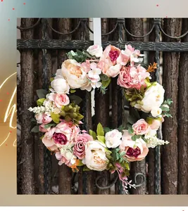 Close-up of artificial pink peony and rose wreath hanging on dark wood fence