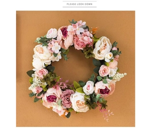 Close-up of pink and red artificial peony wreath on a textured warm background