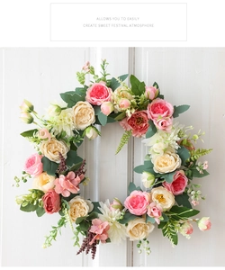 Détail d'une couronne de roses en soie avec feuilles vertes sur une porte en bois blanc