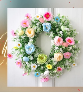 Detalle de corona de Pascua con eucalipto, flores y huevos en puerta de madera blanca