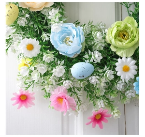 Detalle de corona de Pascua con flores artificiales pastel y huevos de colores moteados