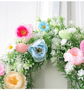 Detalle de corona de Pascua con flores pastel, hojas y huevos de colores moteados