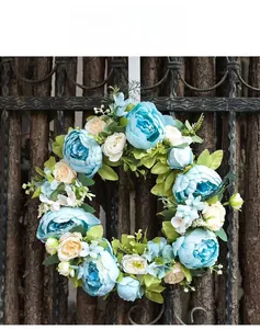 Detail of blue and white silk peony wreath on a rustic dark brown wooden fence background