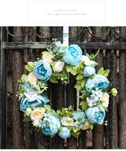 Close-up of artificial blue peony wreath with green leaves on a dark wooden gate