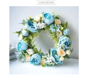 Detail of blue and white silk peonies with lush green leaves on a floral spring wreath