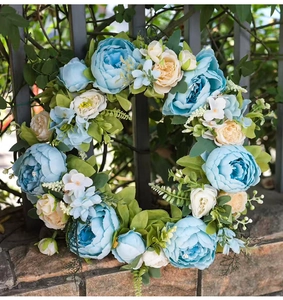 Detail of blue faux peonies and white flower clusters on a spring door wreath