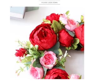Close-up of artificial red peony wreath with green leaves for home wall decoration