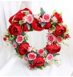 Detailed view of a heart-shaped wreath with deep red peonies and pink roses for wedding decor