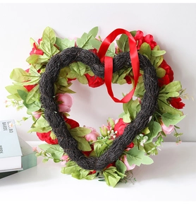 Close-up of heart-shaped peony floral wreath with red silk ribbon and green leaves