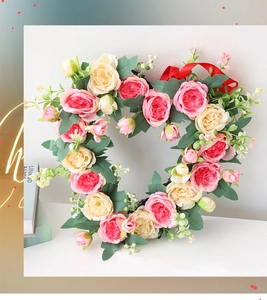 Detail of a heart-shaped wreath with pink roses, green leaves and a red silk ribbon