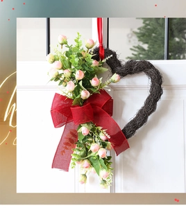 Detalle de corona en forma de corazón con rosas rosas y lazo rojo en la puerta