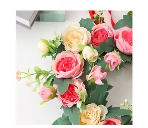 Detailed close-up of pink and cream silk rose wreath with green leaves for wedding decor