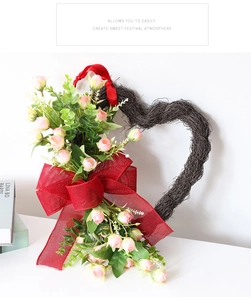 Detalle de corona en forma de corazón con rosas rosas y un gran lazo de arpillera roja