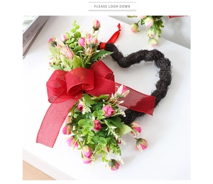 Primer plano de corona de corazón con rosas rosas y un lazo de cuadros rojos