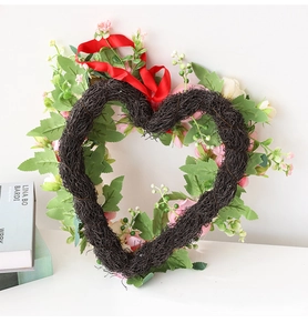 Detail of a handmade heart-shaped vine wreath with pink flowers and a red ribbon