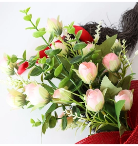 Primer plano de rosas artificiales rosas y hojas verdes con cinta roja en corona de vid