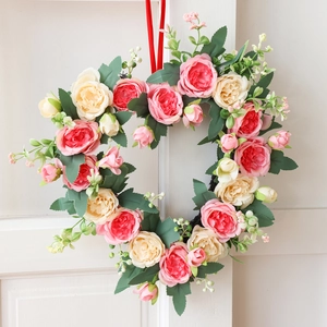 Pink heart-shaped floral wreath with roses and red ribbon for Valentine's home decor