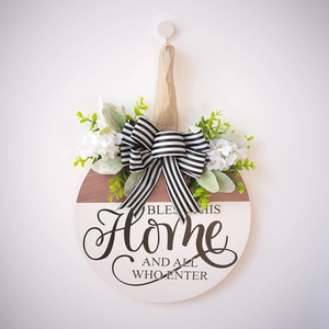 Round wooden welcome sign with green foliage and striped bow for home entrance