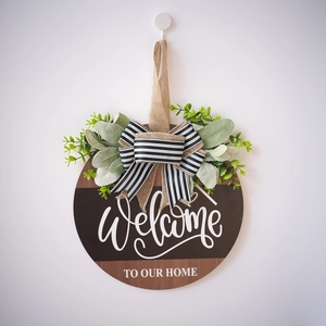 Round wooden welcome sign for front door with burlap bow and artificial greenery