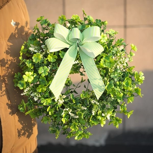 Detail von St. Patrick's Day Kleekranz mit grün gestreifter Schleife in der Hand