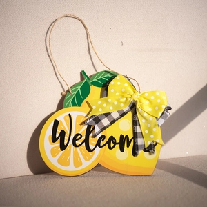 Detalle de cartel de bienvenida de madera con forma de limón, lazo amarillo y cuerda