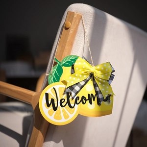 Detalle de cartel de bienvenida de madera con limones amarillos, hojas y lazo de tela
