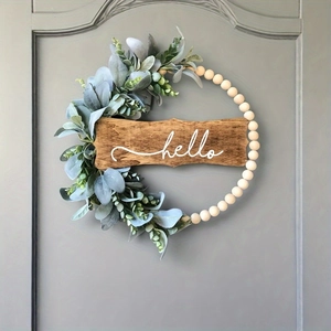 Boho wood bead wreath with eucalyptus leaves and hello sign hanging on a grey door