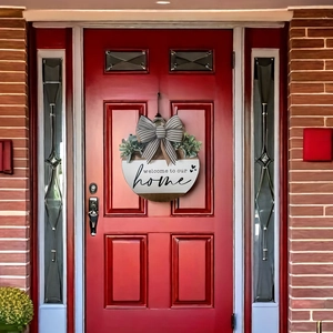 Detail of wooden welcome sign with plaid bow and greenery on a red front door