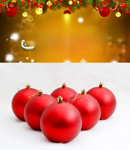 Detail of six matte red Christmas baubles with gold caps on a soft white faux fur surface