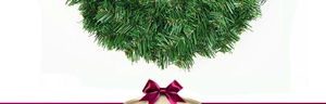 Dettaglio di una corona di Natale in PVC verde decorata con un vivace fiocco di raso viola