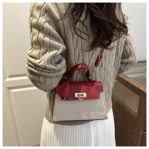 Detail of red and cream contrast bag featuring woven texture and gold metal twist lock