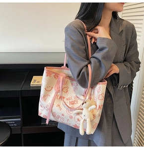 Detail of contrast tote bag with graffiti prints and cute bunny plush charm accessory