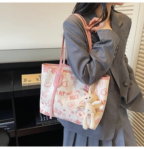 Detail of white tote bag with bear print, pink trim and cute bunny plush charm accessory