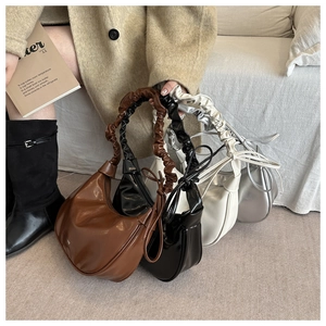 Detail view of crescent handbags with scrunchie handles in brown, black, white, and silver