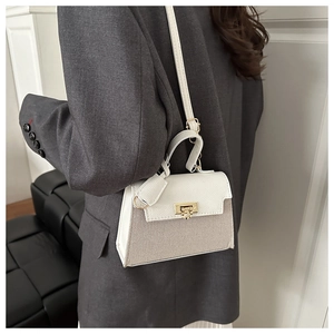 Detail view of woven square crossbody bag with gold buckle on a model in a gray suit