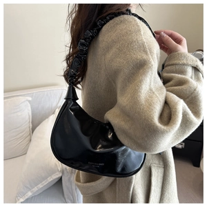 Détail du sac croissant noir brillant avec bandoulière froncée et logo Fanyissa gravé