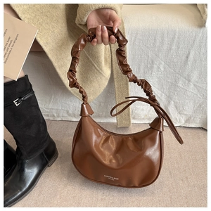 Détail d'un sac demi-lune en cuir marron avec une bandoulière plissée style nuage