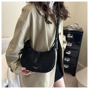 Detail of black nylon crescent bag with drawstring pleated texture and adjustable strap