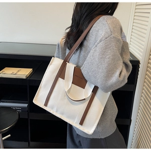 Detail of canvas tote bag with long brown shoulder straps shown on a model side view