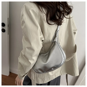 Silver metallic crescent crossbody bag with knotted strap detail worn by a model