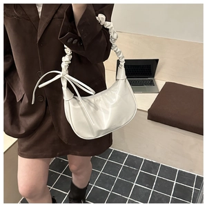 Détail du sac demi-lune blanc crème avec poignée plissée et nœud décoratif en ruban