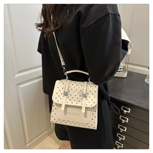 Polka dot crossbody bag shown on a model highlighting its compact size and square shape