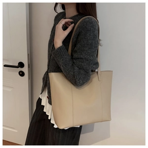 Minimalist beige oversized tote bag in soft leather shown on a model for daily commute