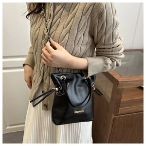 Detalle de bolso tipo cubo negro con cadena dorada y logotipo de moda impreso