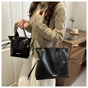 Detail view of black leather tote bag set with gold chain strap and fashion logo