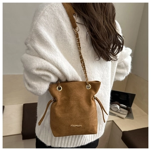 Brown suede bucket bag detail with gold metal chain strap and drawstring fringe
