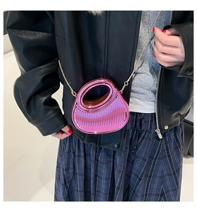 Close-up of metallic pink half-moon bag with pleated texture and round handle worn by model
