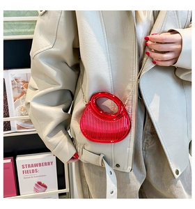 Red acrylic mini bag with vertical texture and golden chain shown on casual outfit
