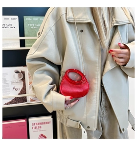 Detail of red acrylic mini bag featuring vertical ridges and a golden chain strap